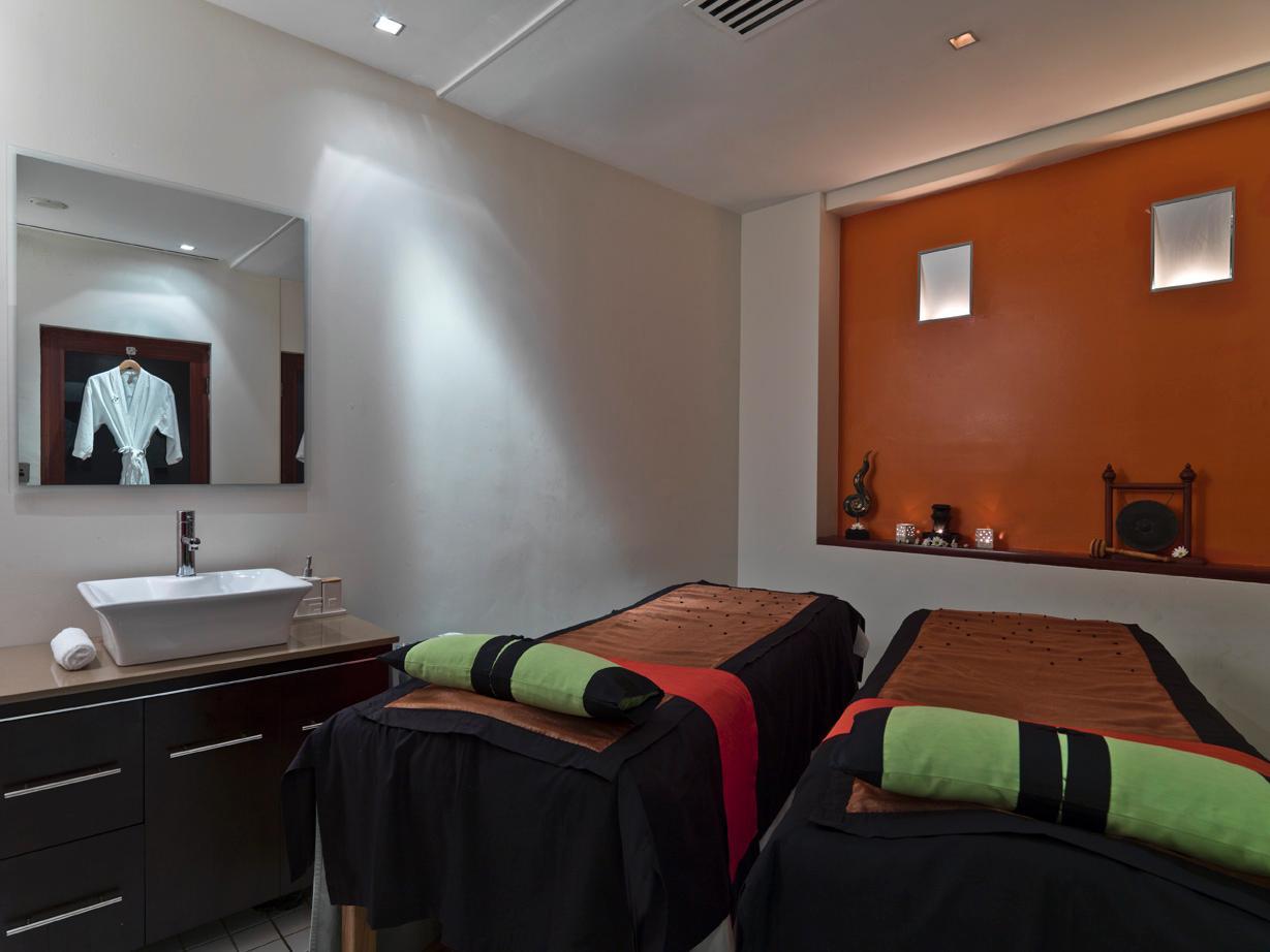 Amora Hotel Jamison Sydney Ngoại thất bức ảnh The photo shows a serene spa treatment room with two massage tables set up side by side. Each table is covered with dark fabric and features neatly rolled towels at the foot—one towel is green and the other is black. There is a modern sink with a min
