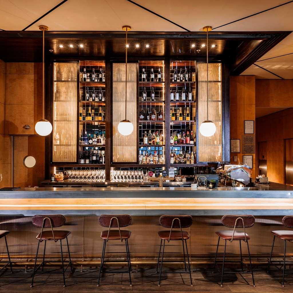 Amora Hotel Jamison Sydney Nhà hàng bức ảnh The photo shows a well-designed bar area. The bar has an elegant, modern aesthetic with a long, polished countertop and several backlit pendant lights hanging above. Behind the bar, there are shelves filled with various bottles of liquor, displayed n