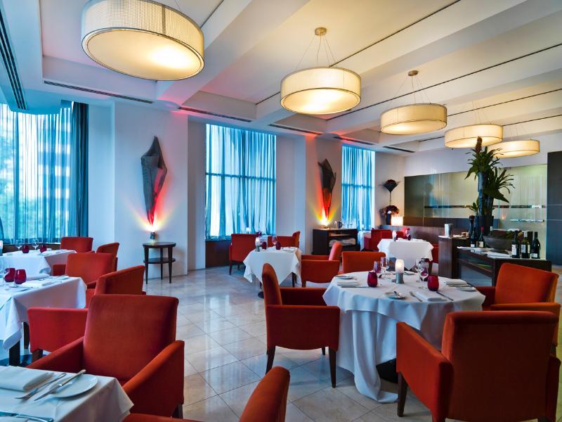 Amora Hotel Jamison Sydney Ngoại thất bức ảnh The photo shows an elegant restaurant interior. The space features stylish red chairs arranged around white tablecloth-covered tables. There are decorative elements like sculptures or artworks on the walls, and large windows covered with sheer curtai