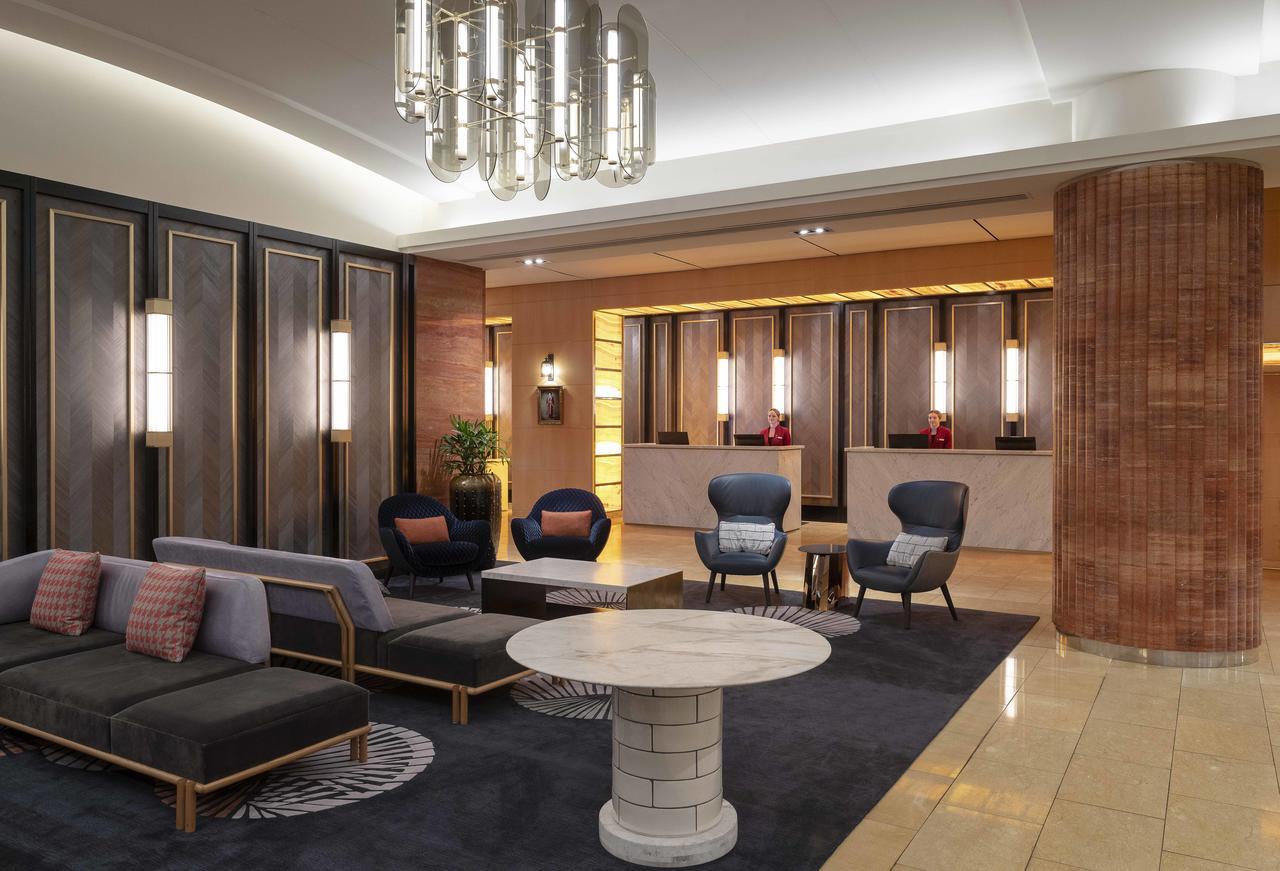 Amora Hotel Jamison Sydney Ngoại thất bức ảnh The photo depicts a modern hotel lobby. It features stylish furniture, including a black and gray seating area with cushions, and two blue accent chairs. A round, white coffee table sits in the center of the seating arrangement. The background shows 