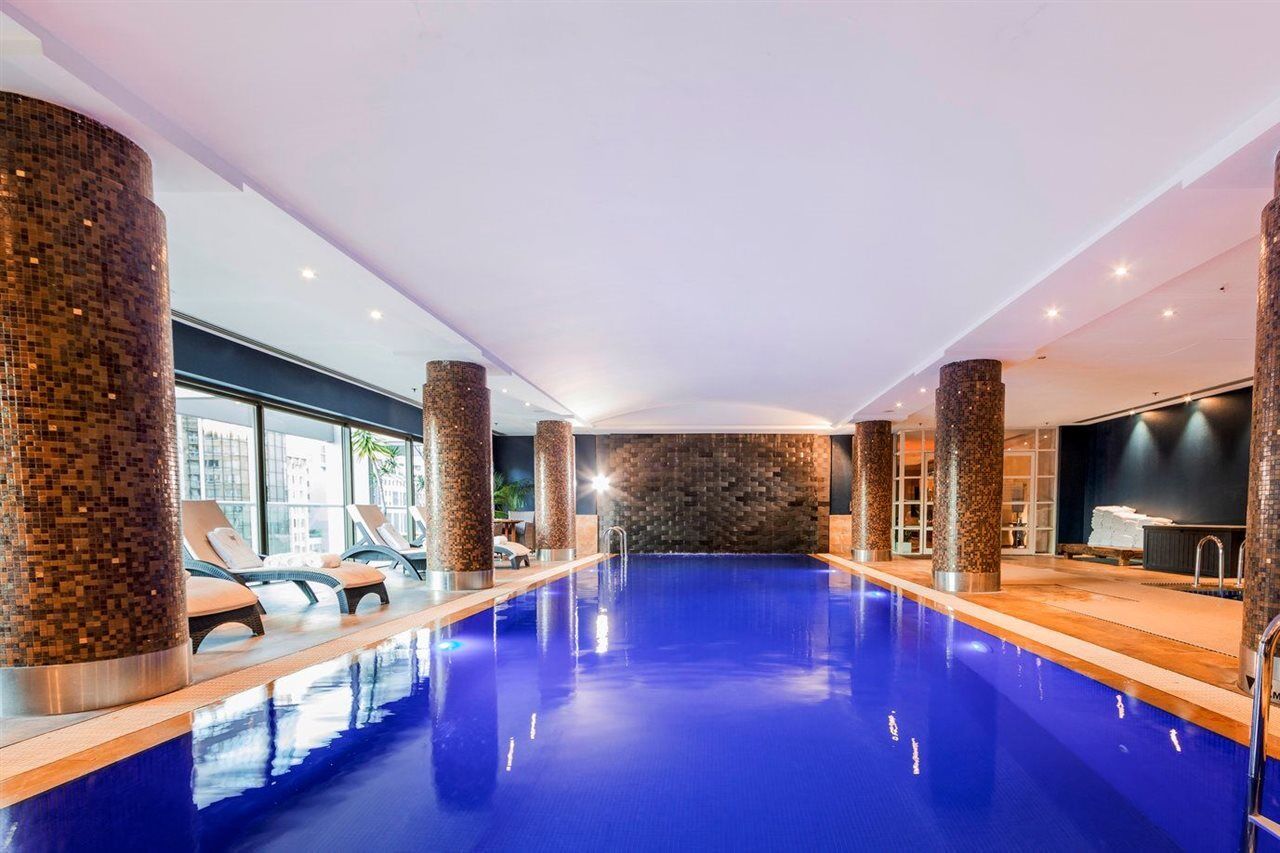 Amora Hotel Jamison Sydney Ngoại thất bức ảnh The photo features an indoor swimming pool with vibrant blue water. The pool area is well-lit, with several sources of light illuminating the space. Surrounding the pool are stylish stone columns, and there are lounge chairs positioned nearby for rel