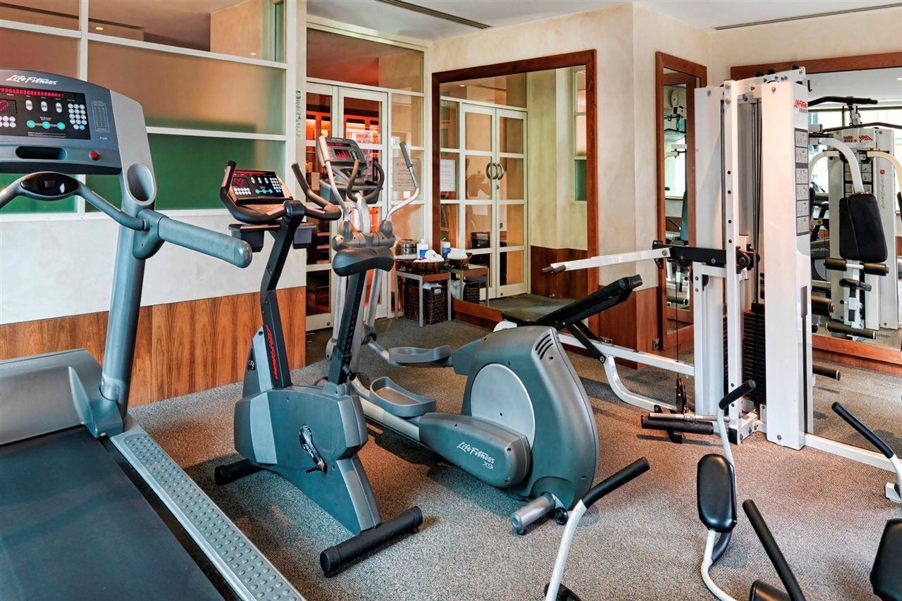 Amora Hotel Jamison Sydney Ngoại thất bức ảnh The photo shows an indoor gym space equipped with various fitness machines. There is a treadmill, an elliptical machine, and a multi-station weight machine. The gym has a clean and modern design, with wooden accents and large windows that allow natur
